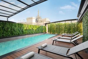 a pool on the roof of a building with chaise lounges at Sina De La Ville in Milan
