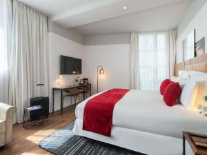 a hotel room with a large white bed with red pillows at Boutet Bastille Hotel Paris - MGallery Collection in Paris +135 photos