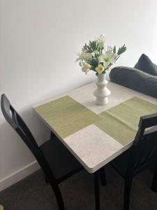 a table and chairs with a vase of flowers on it at Pork pie pad in Melton Mowbray