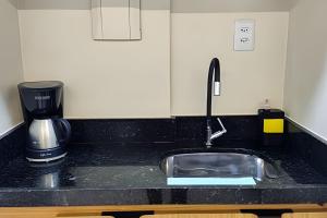 a kitchen counter with a sink and a coffee maker at Refúgio da Praça: Charme e Conforto in Belém