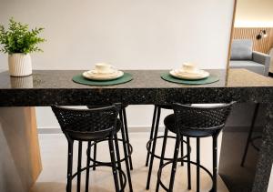 a counter with four bar stools with plates on it at Studio Chico 02 in Espirito Santo Do Pinhal