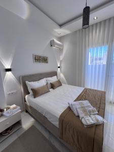 a white bedroom with a large bed and a window at Résidences kenza in Kelibia