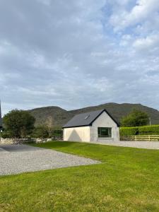 a white house with a black roof on a grass field at Little Hills in Westport