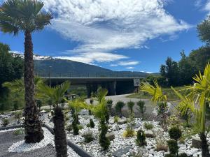 a garden with palm trees and a bridge at T2 modern in Frontenex-Villard-Rosset