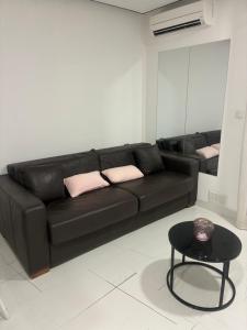 a black couch in a living room with a table at Studio jardin cap d Agde in Cap d'Agde +1 photo