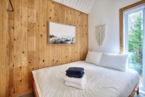 ein Schlafzimmer mit Bett, Holzwänden und einem Fenster in der Unterkunft Nature Getaway with Lake, Horseback Riding & BBQ in Sainte-Marguerite