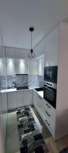 a kitchen with white cabinets and a tv and a microwave at Apartman Eldin Panonika in Tuzla +9 photos