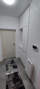 a kitchen with white cabinets and a rug on the floor at Apartman Eldin Panonika in Tuzla
