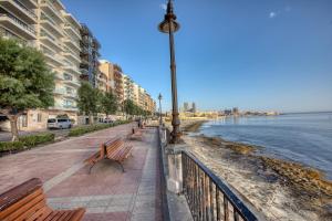a street with benches next to the water and buildings at NEW - 2BR Beach side apt by SF HOMES in Sliema