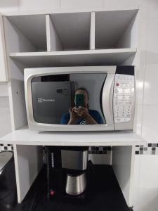 a man taking a picture of himself in a microwave at Apartamento térreo bem equipado, fácil acesso in Canoas