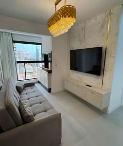 a living room with a couch and a flat screen tv at Itapema in Itapema