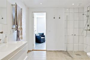 a white bathroom with a shower and a blue couch at Villa Sandby B&B in Borrby +104 photos