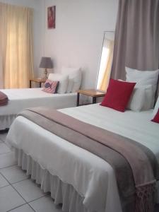 two beds in a hotel room with red and white pillows at Green leaves in Mahikeng