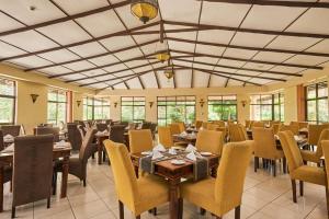 a dining room with tables and chairs and windows at Sagana Getaway Resort in Maranjua