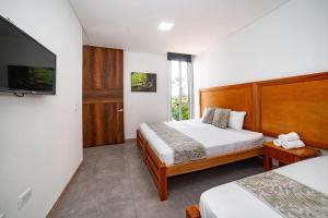 a bedroom with two beds and a flat screen tv at Casa campestre en el Eje Cafetero in Circasia