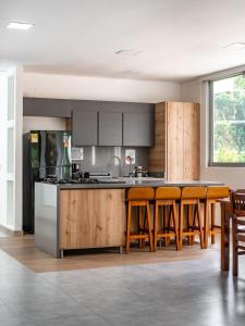 a kitchen with wooden cabinets and a bar with stools at Casa campestre en el Eje Cafetero in Circasia