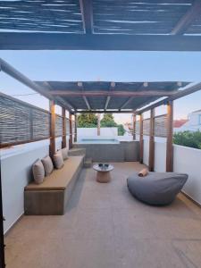 a covered patio with couches and a table at House Marigo Suites in Koskinou