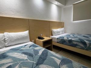 ein Hotelzimmer mit zwei Betten und einem Spiegel in der Unterkunft Hotel Nueva Zelanda in León + 16 Fotos