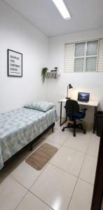 a bedroom with a bed and a desk with a computer at Pousada da Juh in Campo Grande