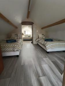 two beds in a room with a wooden floor at Douce Campagne in Clermont-Créans
