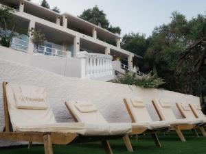 a group of lounge chairs in front of a building at Poseidon Complex in Paleokastritsa
