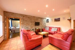 a living room with red furniture and a stone wall at Elm Cottage in Aberfeldy