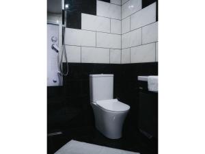 a bathroom with a toilet and a black and white tiled wall at Poseidon Complex in Paleokastritsa