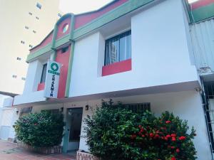 a white building with flowers in front of it at Hotel Charmin in Gaira