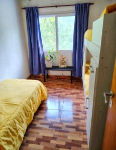 a bedroom with a bed and a window with blue curtains at La Elegida Villars in General Las Heras