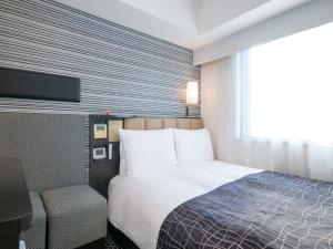 a hotel room with a bed and a flat screen tv at APA Hotel Keisei Ueno Ekimae in Tokyo