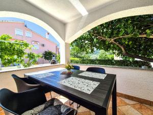 a table and chairs in a patio with a tree at Apartments Benkovic in Baška