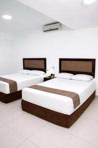 zwei Betten in einem Zimmer mit weißen Wänden in der Unterkunft Win & Win Hotel & Casino Piura in Piura