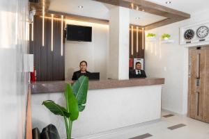 zwei Personen sitzen an einem Rezeptionstresen in einer Lobby in der Unterkunft Win & Win Hotel & Casino Piura in Piura