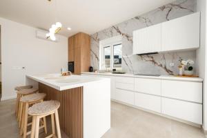 a kitchen with white cabinets and a counter and stools at Villa Infinity in Rtina