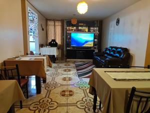 a living room with a tv and a couch and tables at Hostal Amazonas in Chivay