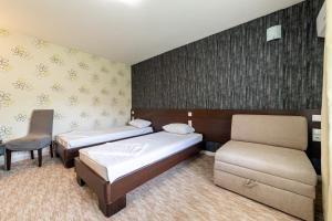 a hotel room with two beds and a chair at Aparthotel HayatHills in Sarajevo