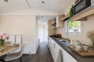 a kitchen with a sink and a counter with a table at Sfeervol boshuisje op de Veluwe Vossenberg in Nunspeet +34 photos