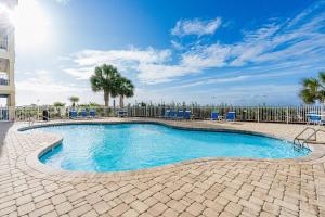 a swimming pool with blue chairs and a fence at Marlin Key 3B in Orange Beach +42 photos