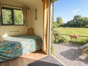 a bedroom with a bed and a sliding glass door at The Three Spaniels Shepherds Hut in Llanybyther +9 photos