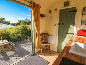 a door leading to a patio with a chair outside at The Three Spaniels Shepherds Hut in Llanybyther