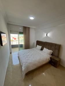 a bedroom with a large bed with white sheets at Baya Residentie in Temara