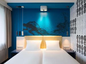 a bedroom with two beds and a blue wall at ibis Styles Haarlem City in Haarlem