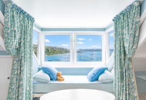 a window seat with a teddy bear sitting in front of a window at An Glas Bras - By Rowes Retreats in Falmouth