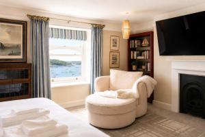 a living room with a chair and a fireplace at An Glas Bras - By Rowes Retreats in Falmouth