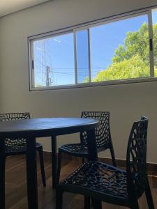 a table and chairs in a room with a window at Harmony House Hospedagem in Votuporanga