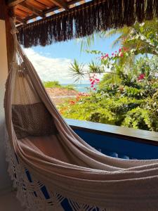 a hammock in front of a window with a view at Pousada Nascente do Sol in Ilha de Boipeba