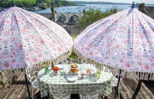 two pink umbrellas over a table with food on it at An Glas Bras - By Rowes Retreats in Falmouth