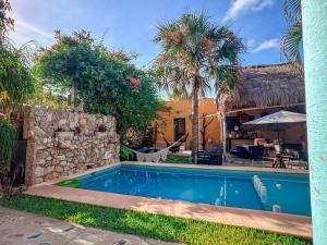 a pool in front of a house with palm trees at Casa Aluxes Hotel in Valladolid