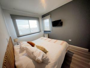 ein Schlafzimmer mit einem Bett mit zwei Kissen und einem Fenster in der Unterkunft LEVEL Terrazas premium con parrillas privadas in Bahía Blanca
