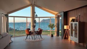 a dining room with a table and chairs and a view of the ocean at Oceanfront Infinity Lodge, Lofoten in Vestvågøya